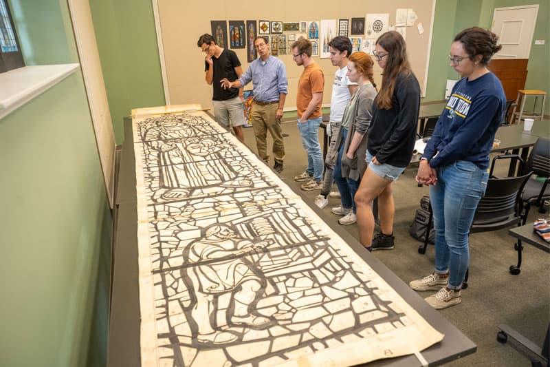 Professor Stephen Hartley and students examine the full-scale cartoon of the Protestant Stream of Christianity window designed by 查尔斯·Z. 劳伦斯在华盛顿特区的国家大教堂. 